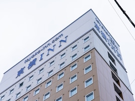 Un edificio con un letrero que dice "Toyoko Inn" y una dirección de sitio web "toyoko-inn.com".