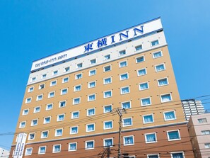 Un edificio de hotel de varios pisos con un letrero que dice "Toyoko Inn" y una dirección web.