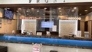 A reception area with a marble counter, a 'FRONT' sign above, and a digital screen displaying information.