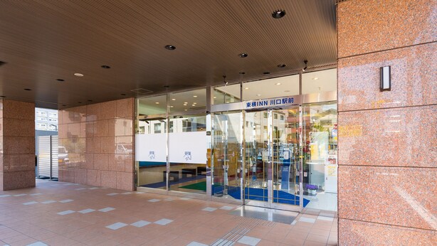 A hotel entrance with a tiled floor, a glass door with signage, and a ceiling with recessed lighting.