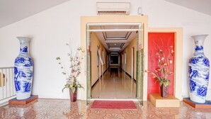 A hallway with large blue vases, a red door, and a tiled floor. - Hotel O Siwalankerto Near Surabaya Carnival (Surabaya)