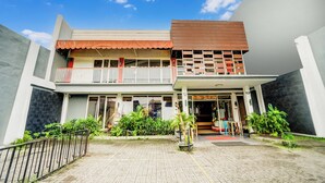 A two-story building with a balcony, a covered entrance, and a paved courtyard. - Hotel O Siwalankerto Near Surabaya Carnival (Surabaya)