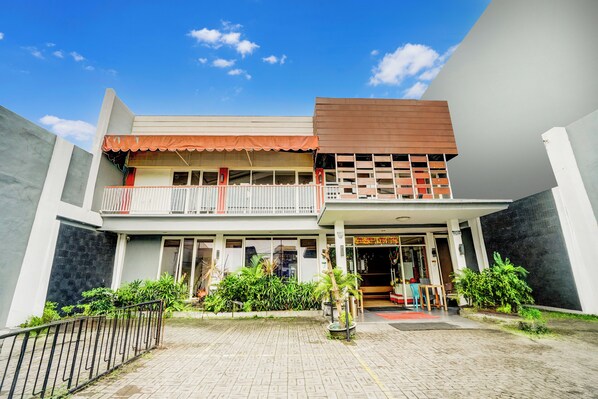 A two-story building with a balcony, a covered entrance, and a paved courtyard. - Hotel O Siwalankerto Near Surabaya Carnival (Surabaya)