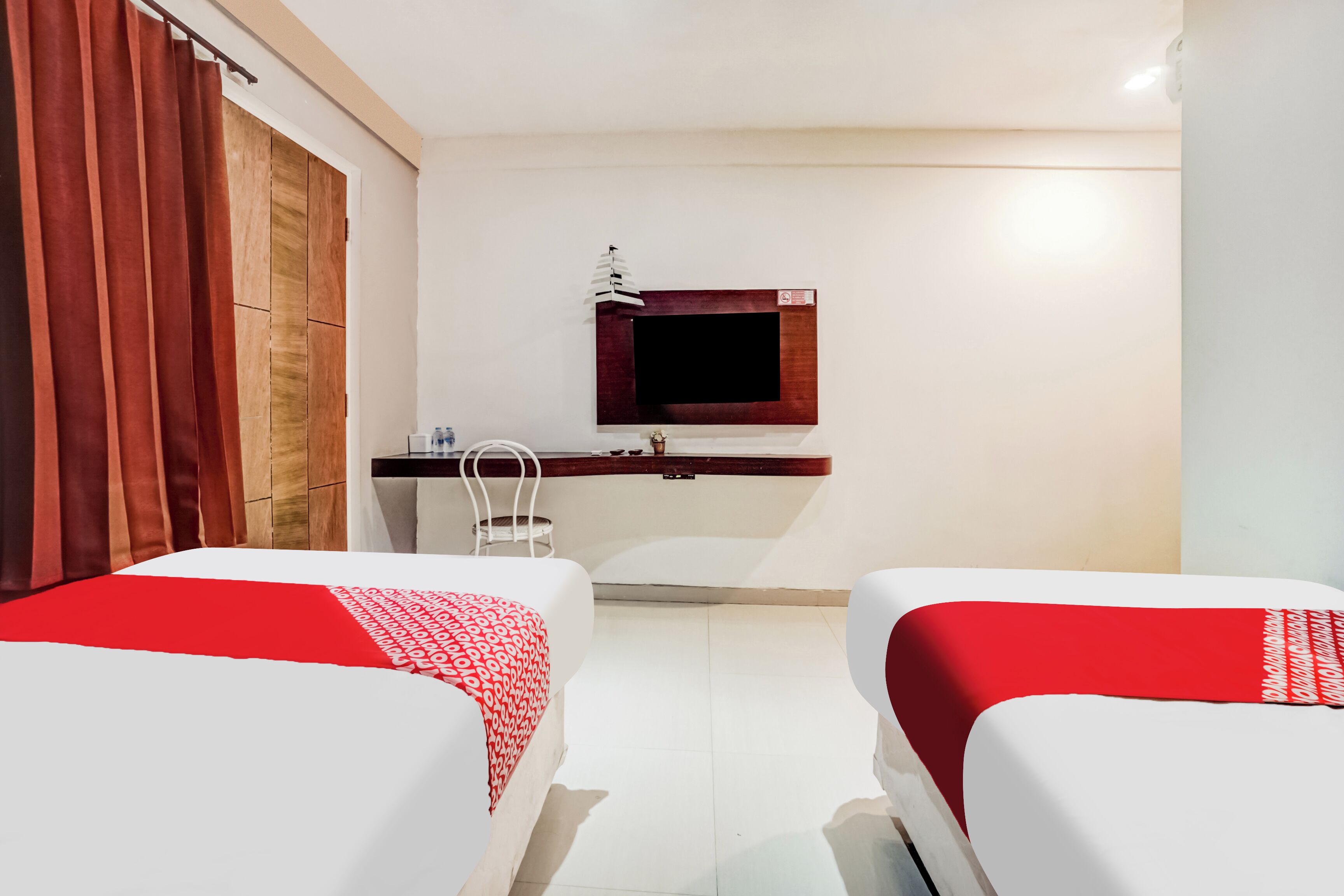 A hotel room with two beds, a desk, a TV, and a wardrobe.