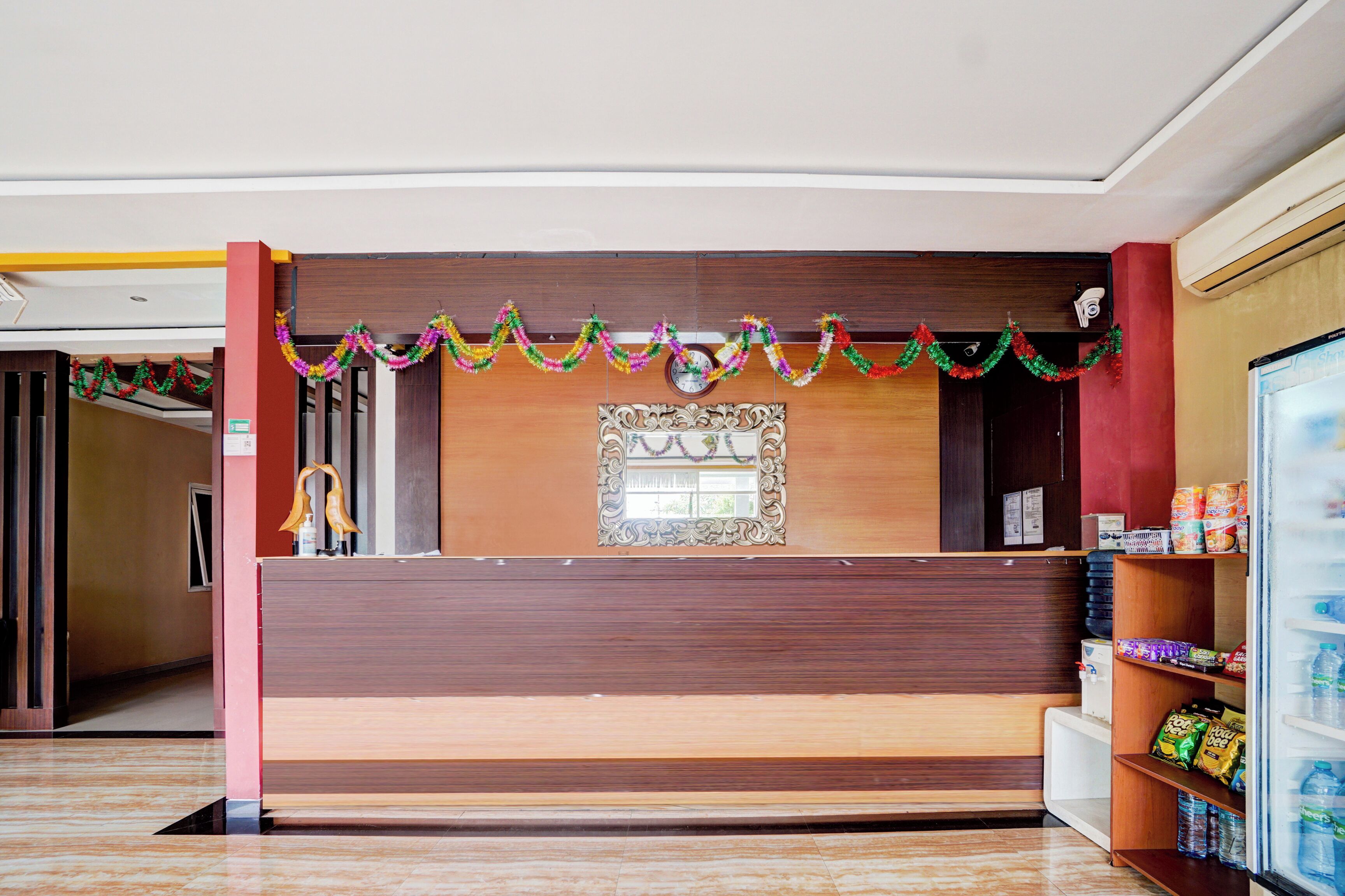 A reception area with a wooden counter, a decorative mirror, and a shelf with snacks.