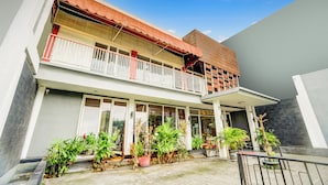 A two-story building with a balcony, potted plants, and a clear sky. - Hotel O Siwalankerto Near Surabaya Carnival (Surabaya)
