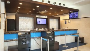 Ein Empfangsbereich mit einem 'FRONT'-Schild, einem digitalen Bildschirm und einem Selbstbedienungsterminal.