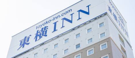 Un edificio de hotel con un letrero que dice 'toyoko-inn.com' y 'TOYOKO INN' en inglés.