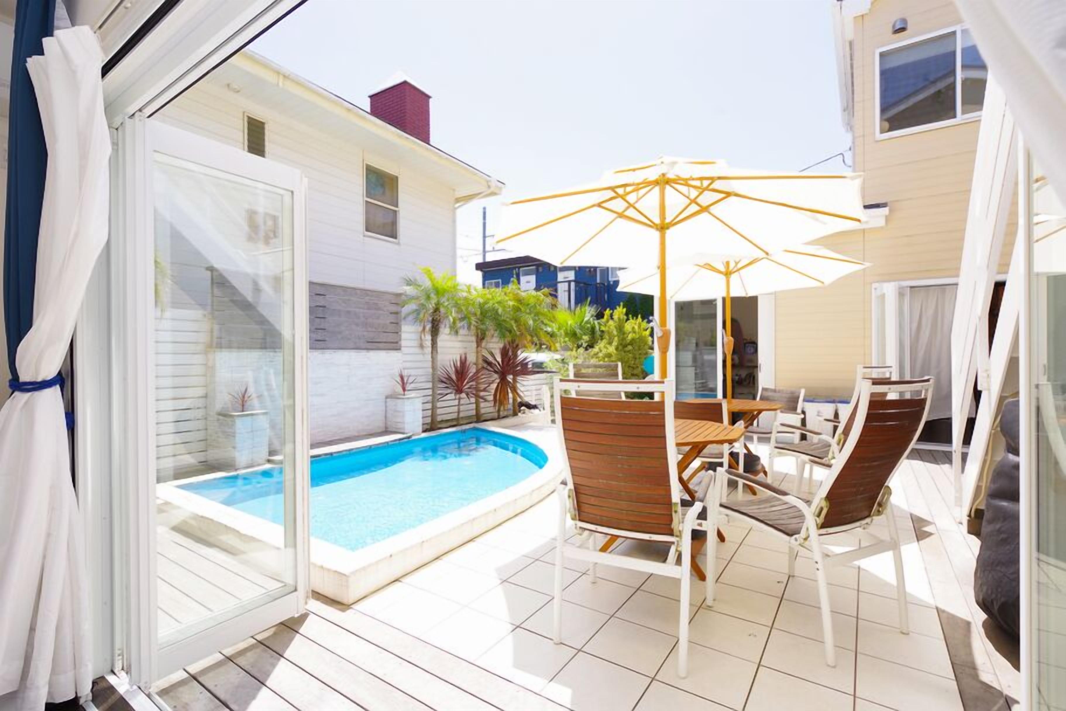 An outdoor patio with a pool, chairs, and a table.