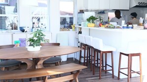 Una cocina moderna con una isla central, armarios blancos y un comedor con mobiliario de madera.