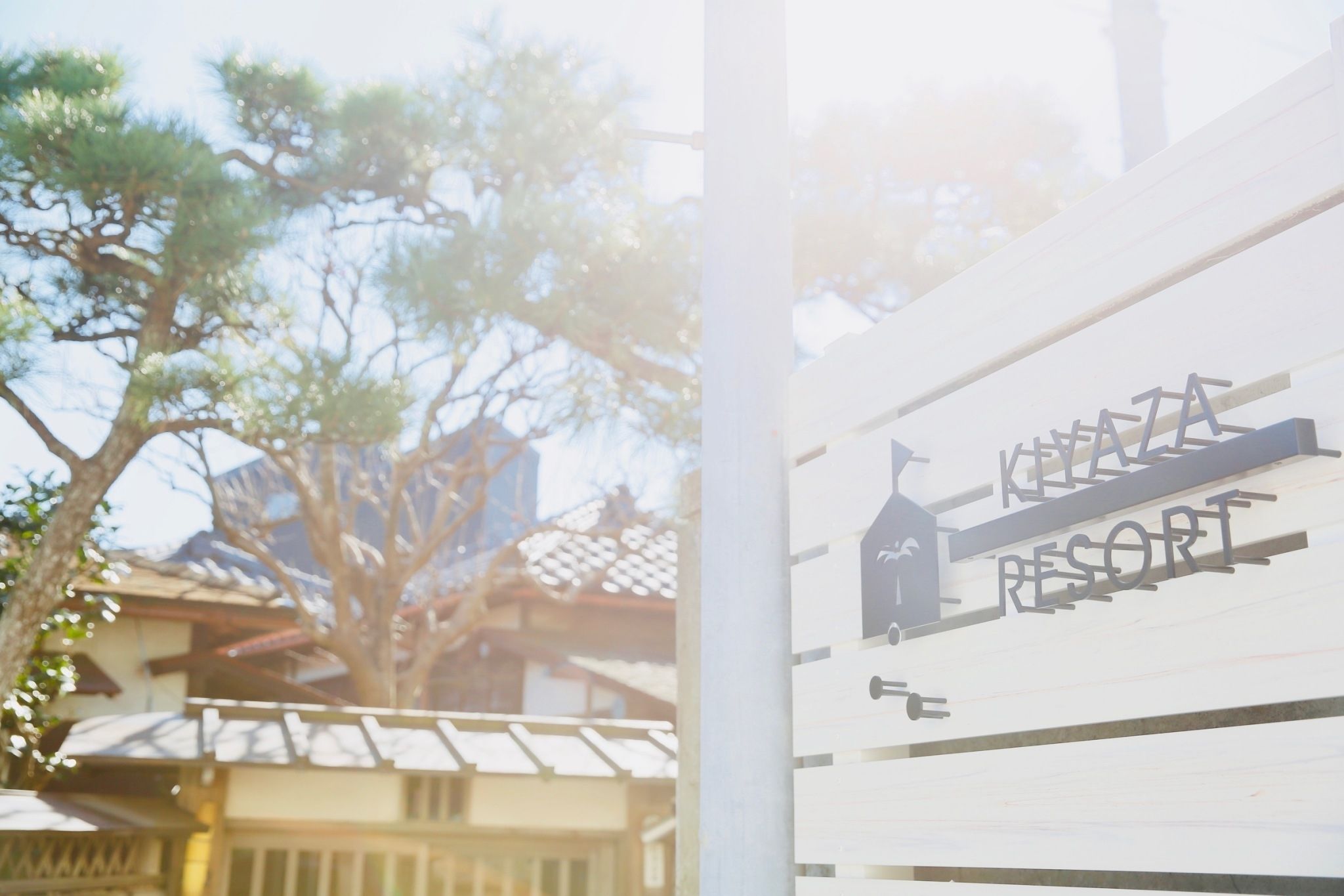 A sign for Koyamada Resort with a silhouette of a building and a tree.
