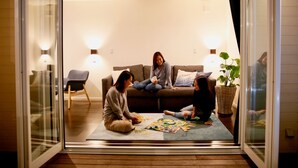 Una sala de estar acogedora con un sofá y sillones, una mesa de centro con juegos de mesa y una planta en maceta.