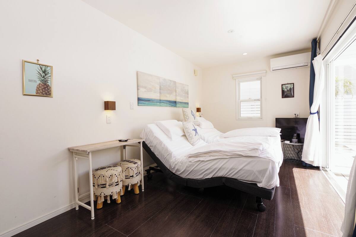 A bedroom with a bed, a small table, a chair, and artwork on the walls.