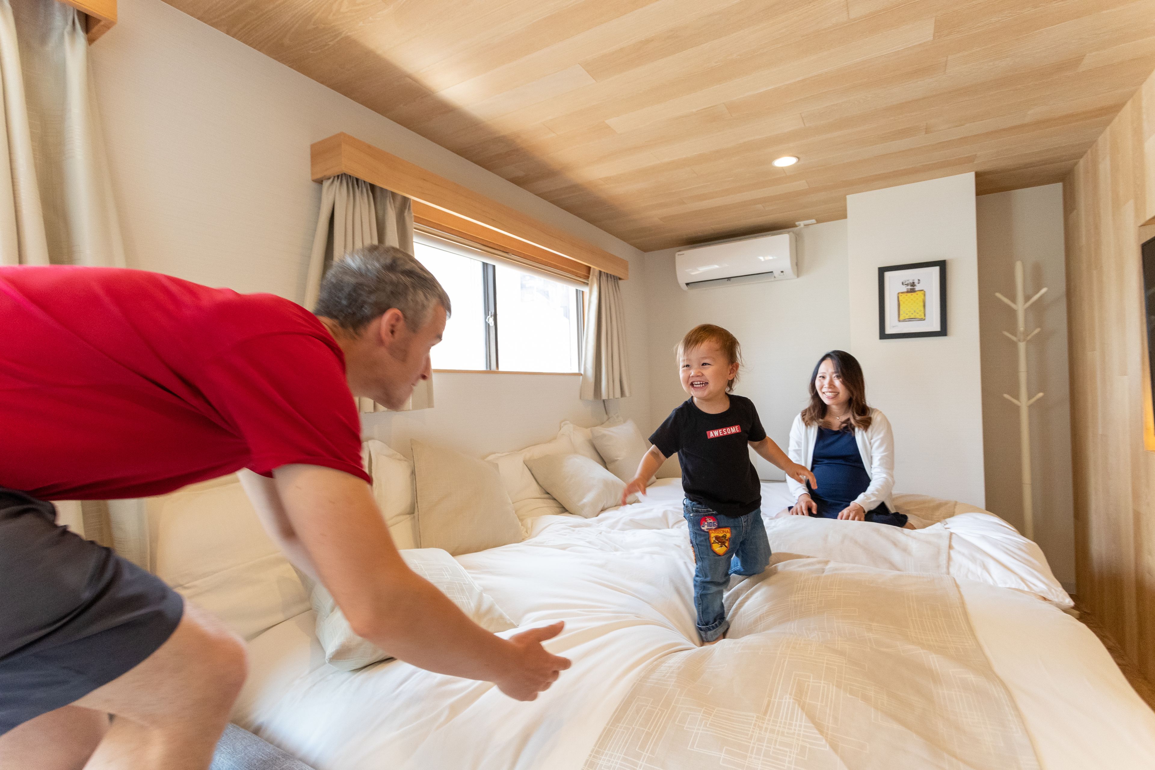 Una habitación con cama, ventana con cortinas, aire acondicionado y perchero.