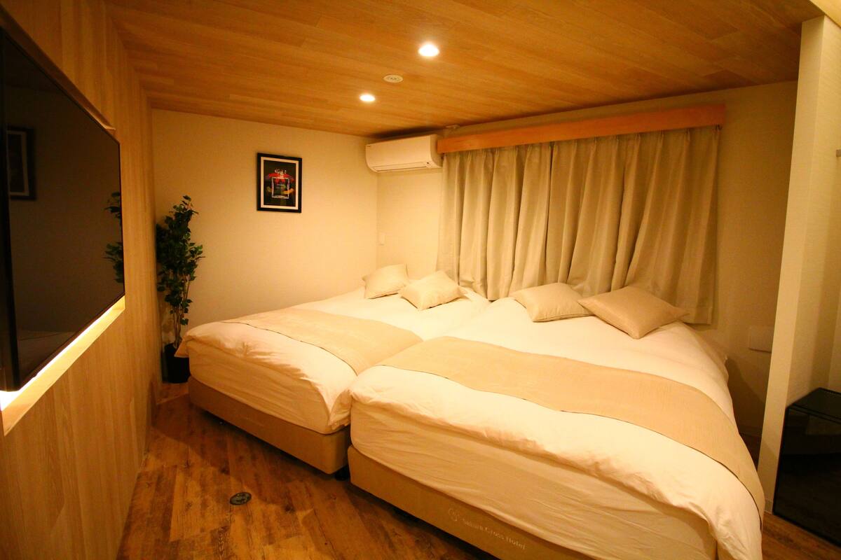 Une chambre avec deux lits, une plante en pot et un appareil de climatisation.