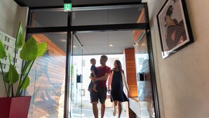 Uma família entrando em um edifício por uma porta de vidro.