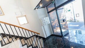 Um interior moderno com escada, porta de vidro para o exterior e painel de controle fixado na parede.