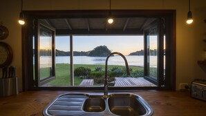 Eine Küche mit doppelter Spüle, Holz Arbeitsplatte und Blick auf einen See sowie entfernte Bäume.