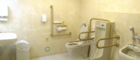 A bathroom with two toilets, a bidet, a sink, and a trash bin.