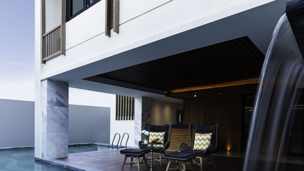 Un bâtiment moderne doté d’une piscine, d’un espace extérieur aménagé et d’une cascade.