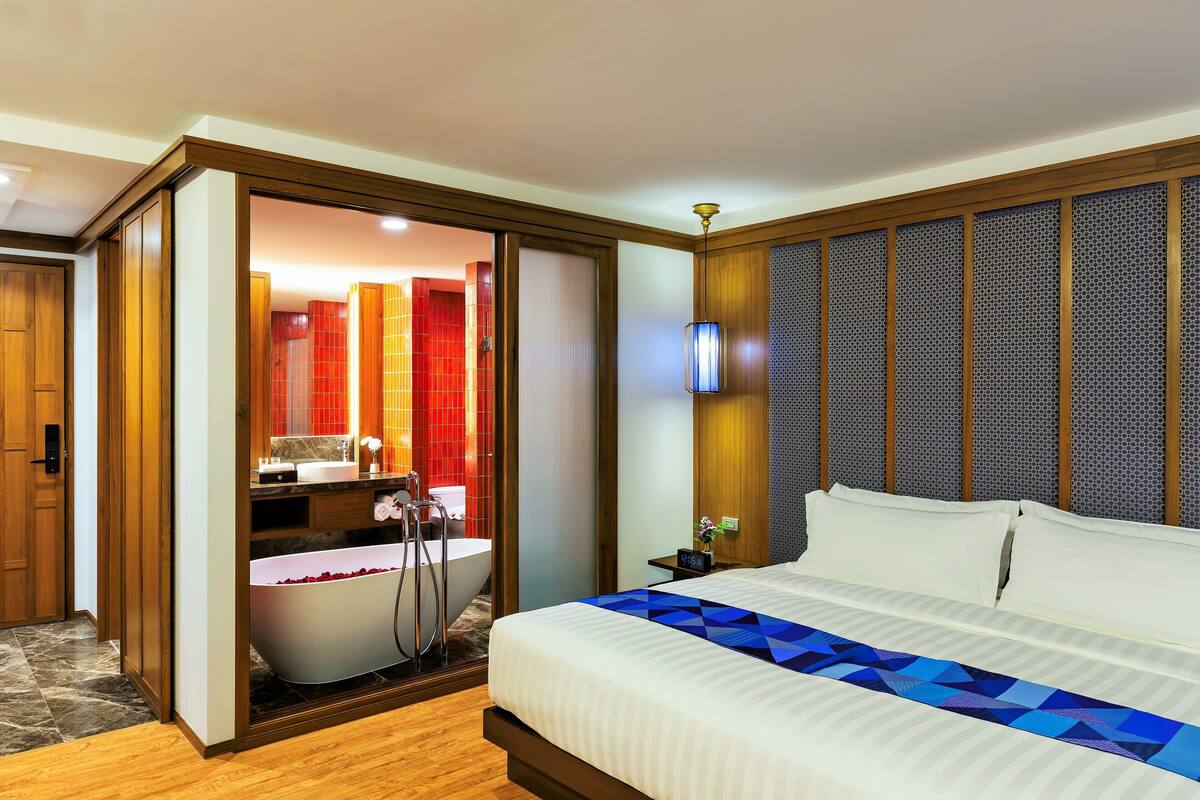 Une chambre d’hôtel avec un grand lit, une baignoire et un mur recouvert de panneaux de bois.