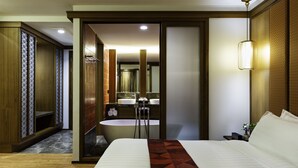 Une chambre d’hôtel avec un grand lit, une salle de bain avec un lavabo et un miroir, et une armoire en bois.