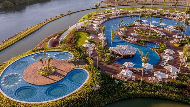 A resort with multiple swimming pools, a marina, and lush greenery.