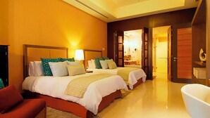 A hotel room with two beds, a sitting area, and a bathtub.