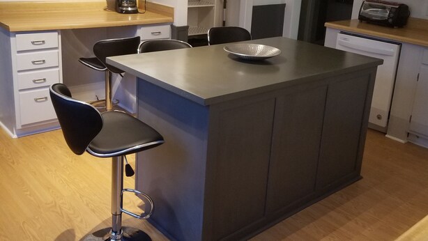 A modern kitchen with a central island, bar stools, white cabinets, and a coffee maker. - Relax Inn this Knotty & Nice entire Home (Evansville)