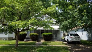 A residential house with a front porch, a driveway, and a parked car. - Relax Inn this Knotty & Nice entire Home (Evansville)