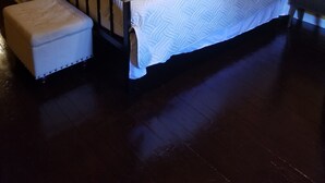 A bedroom with a bed, a nightstand, a lamp, and a small stool. - Relax Inn this Knotty & Nice entire Home (Evansville)