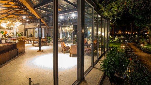 Um interior moderno com paredes de vidro, móveis de madeira e uma área de refeições bem iluminada.