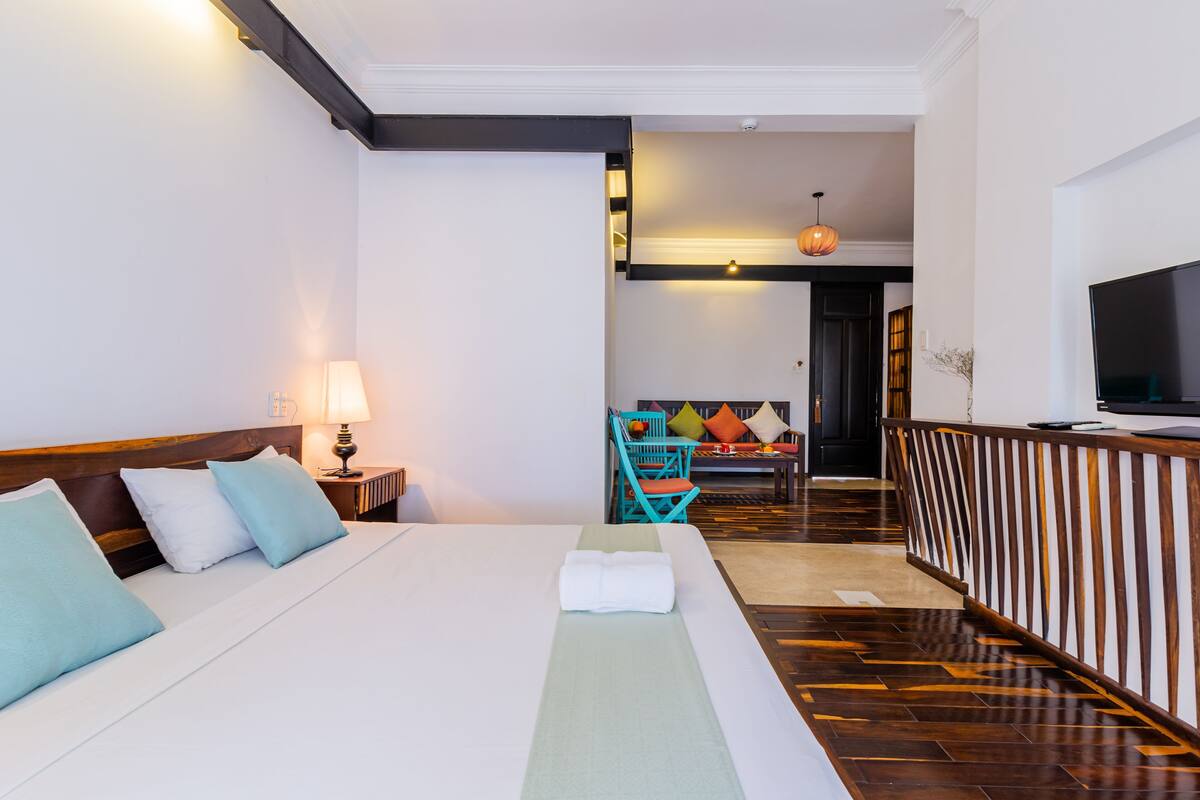 A hotel room with a bed, a TV, a desk, and a chair.