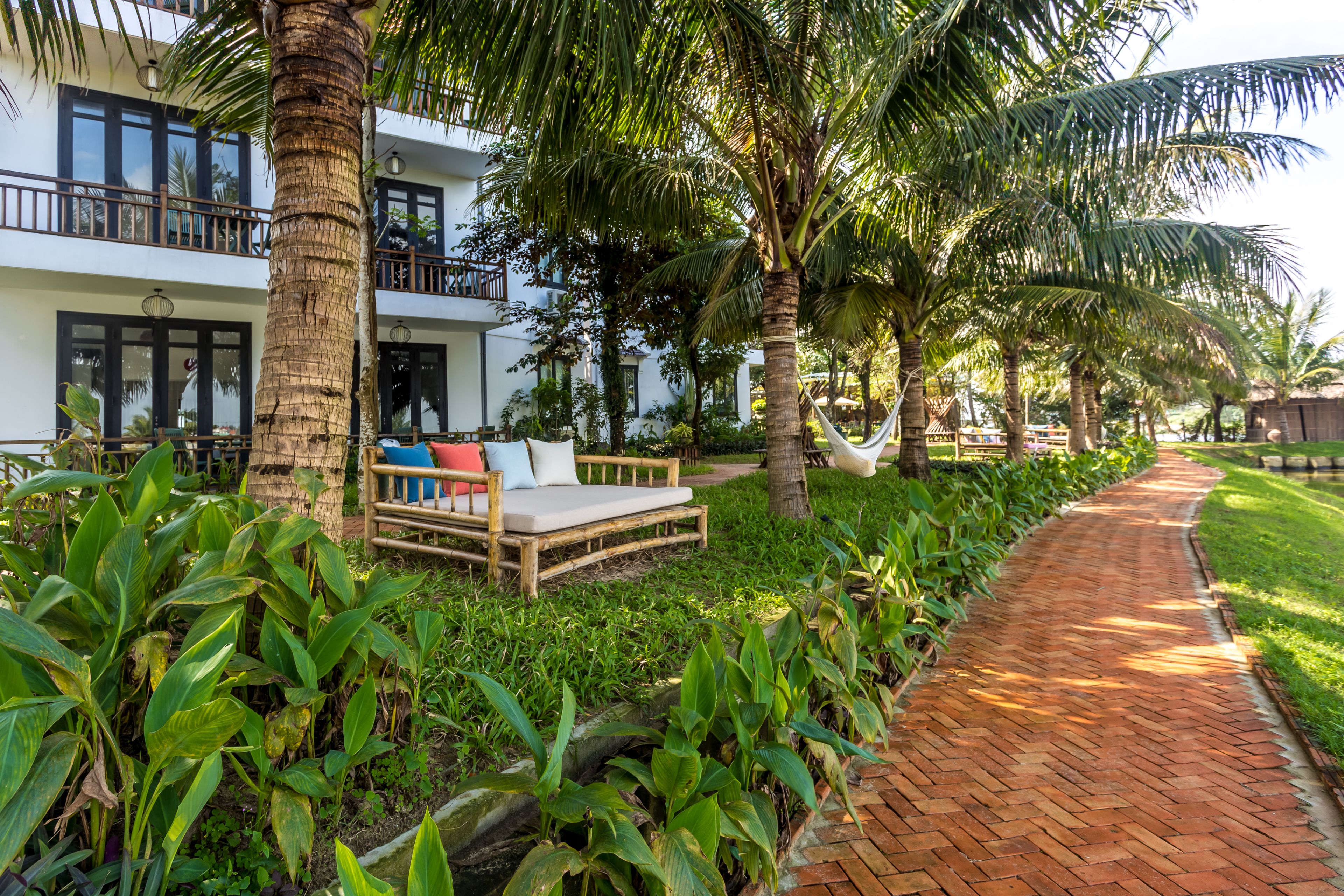 A hotel with a wooden deck, a hammock, and a brick pathway.
