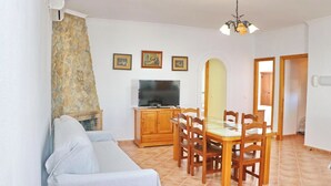 A living room with a sofa, a dining table with chairs, a TV, and framed pictures on the wall. - Perfect house for families with pool (CONIL DE LA FRONTERA)
