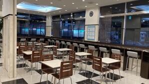 A modern cafeteria with a long counter, multiple tables, and chairs. - Toyoko Inn Tokyo Keihin Tohoku Line Oji Station Kita (Tokyo)