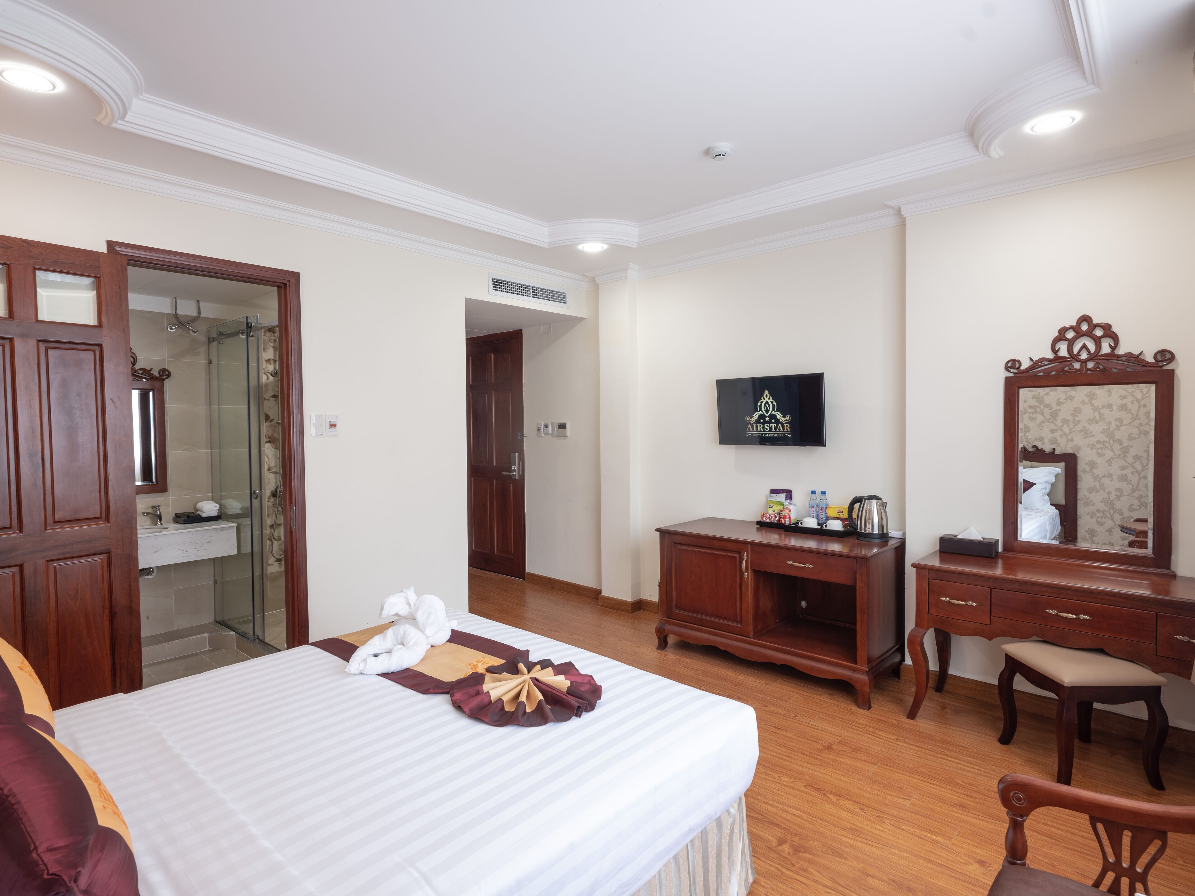 A hotel room with a bed, a wooden dresser, a television, and a mirror.