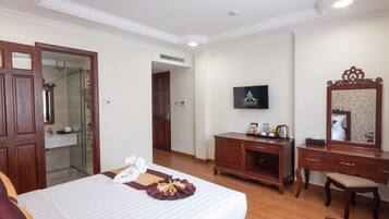 A hotel room with a bed, a wooden dresser, a television, and a mirror.