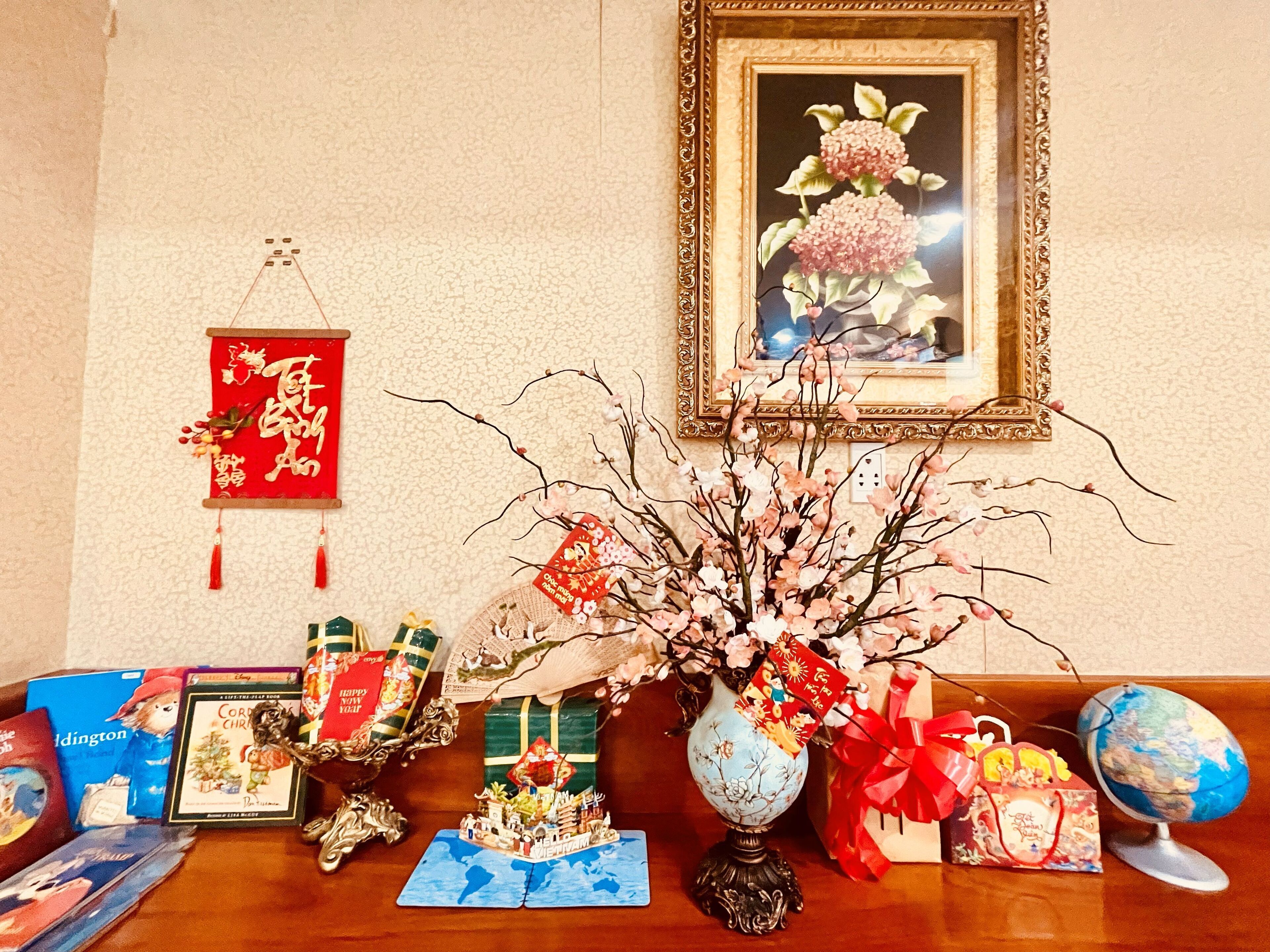 A table with various items including a vase with branches, a framed painting, and several wrapped gifts.