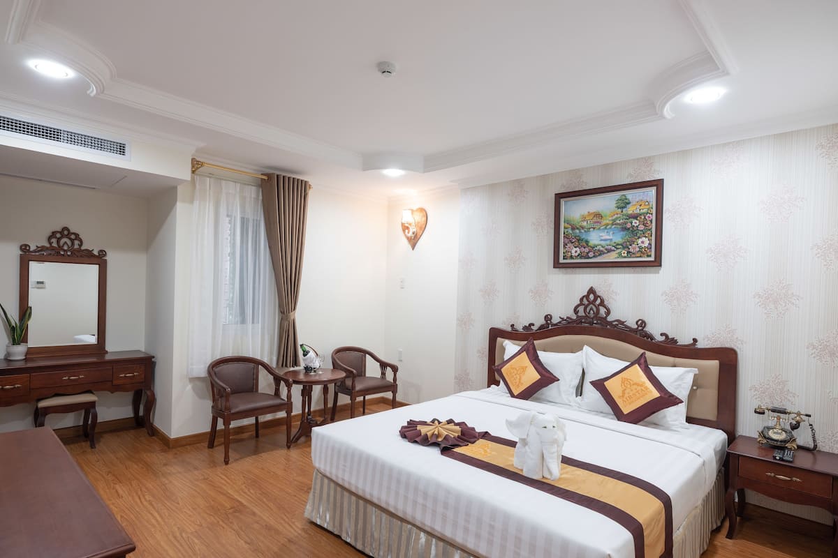 A hotel room with a large bed, a desk, and a chair.
