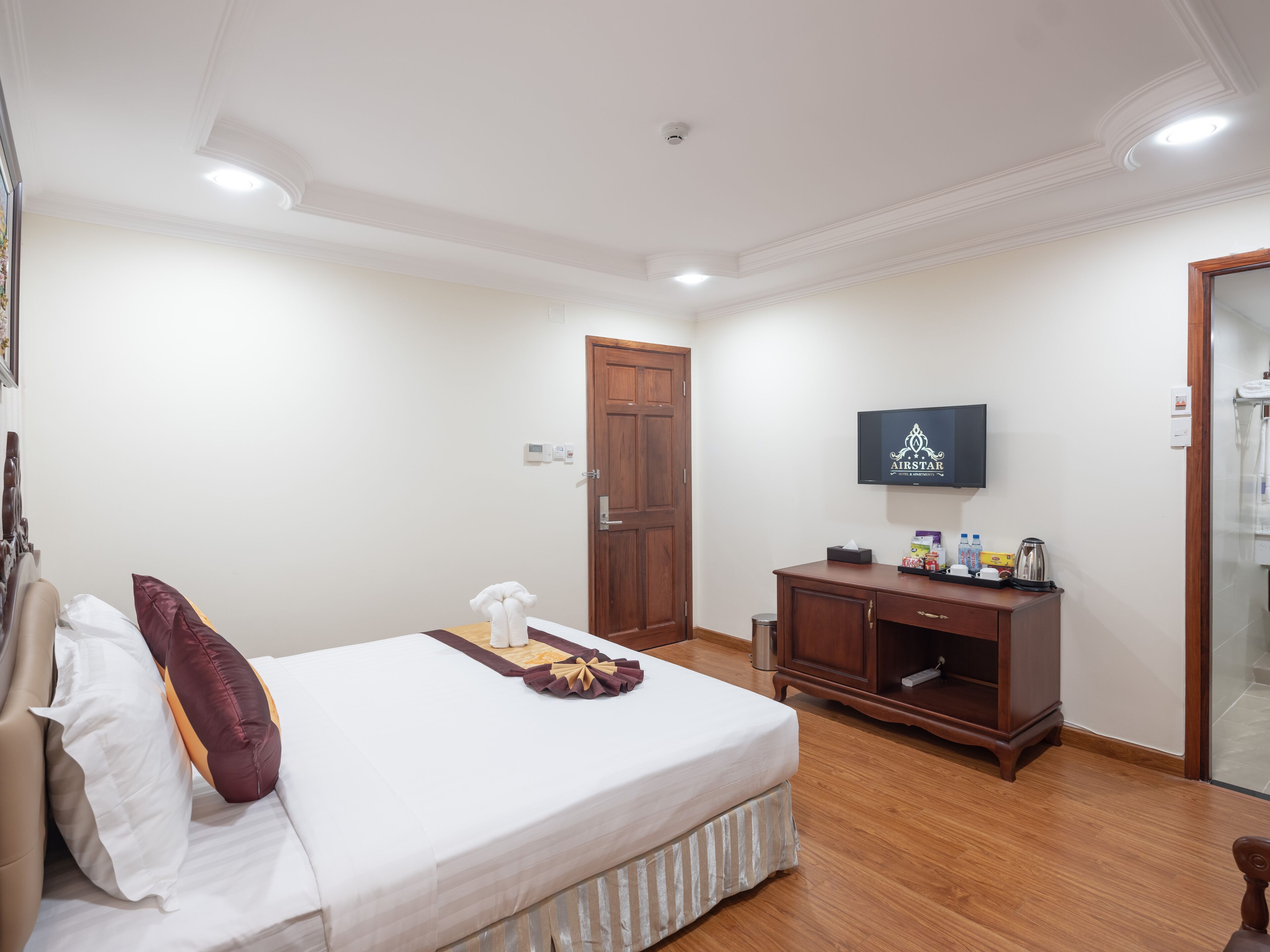 A hotel room with a bed, a wooden cabinet, a television, and a door.