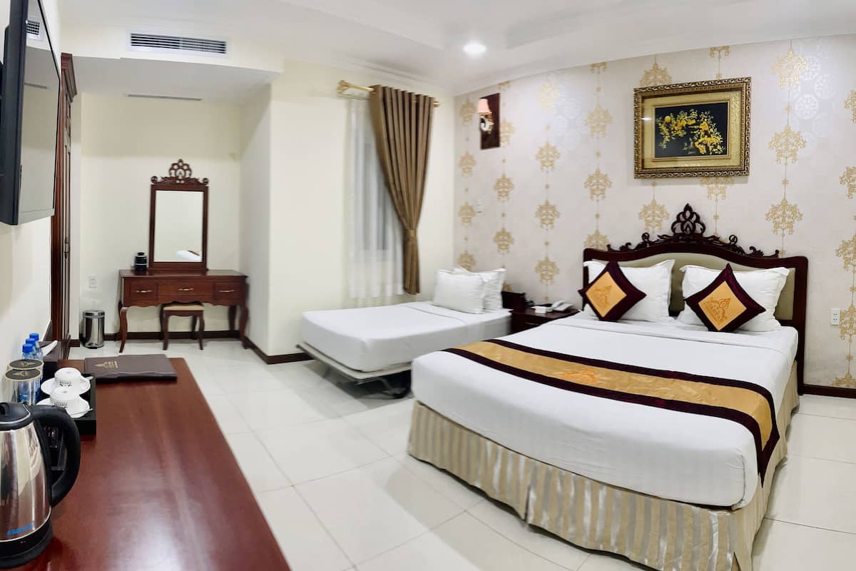 A hotel room with two single beds, a wooden desk with a chair, a large mirror, and a television.
