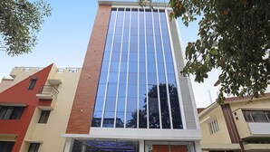 Un bâtiment moderne doté d’une façade en verre, d’une couleur extérieure rouge et beige, et d’une entrée sécurisée par un portail.