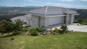 A modern house with a sloped roof, a garage, and a view of a valley. - 6 Barquentine (Knysna)