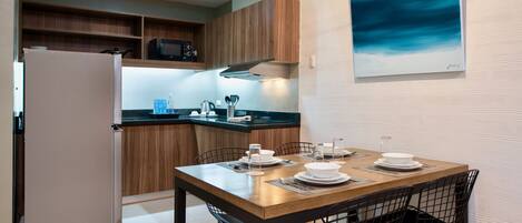 A modern kitchen with wooden cabinets, a built-in microwave, and a dining area with a wooden table and chairs.
