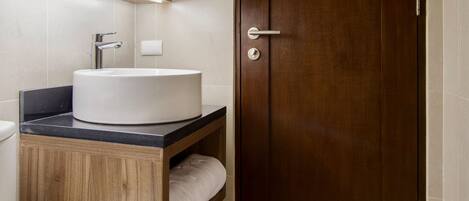 A bathroom with a wooden vanity, a white sink, and a mirror above it.