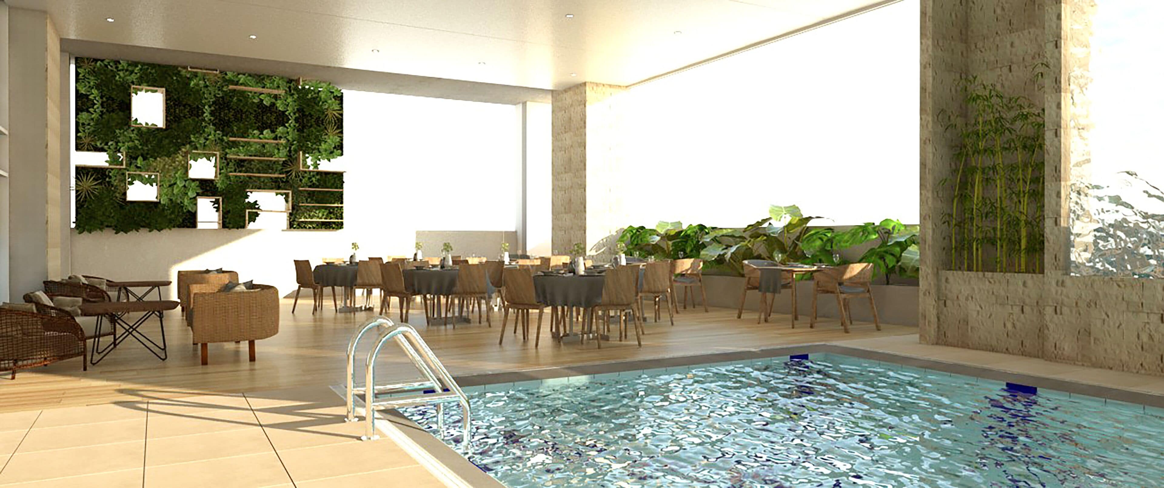 A spacious indoor pool area with a clear view of the pool, surrounded by comfortable seating and tables, and a wall adorned with greenery.