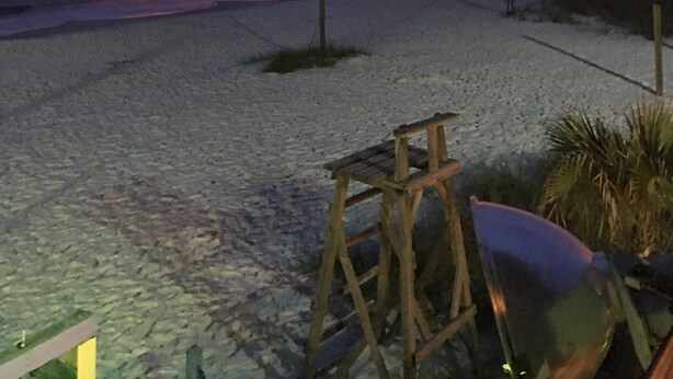 Ein Strand mit einer Holzkonstruktion im Vordergrund, einem Holzzaun und freiem Blick auf den Ozean.