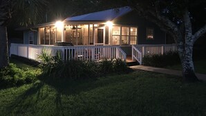 Ein Haus mit überdachter Veranda, Grill und gepflegtem Rasen.