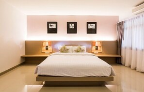 Une chambre d’hôtel moderne avec un grand lit, des lampes de chevet et trois œuvres d’art encadrées accrochées au mur.